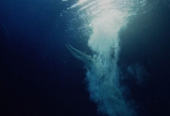En mann svømmer under vann mot overflaten